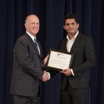 Doctor Potteiger posing for a photo with an award recipient in a black suit and an off white shirt